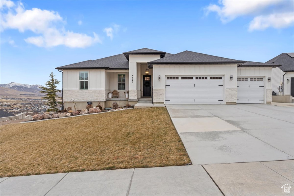 View of front of property with a mountain view, a garage, and a front yard