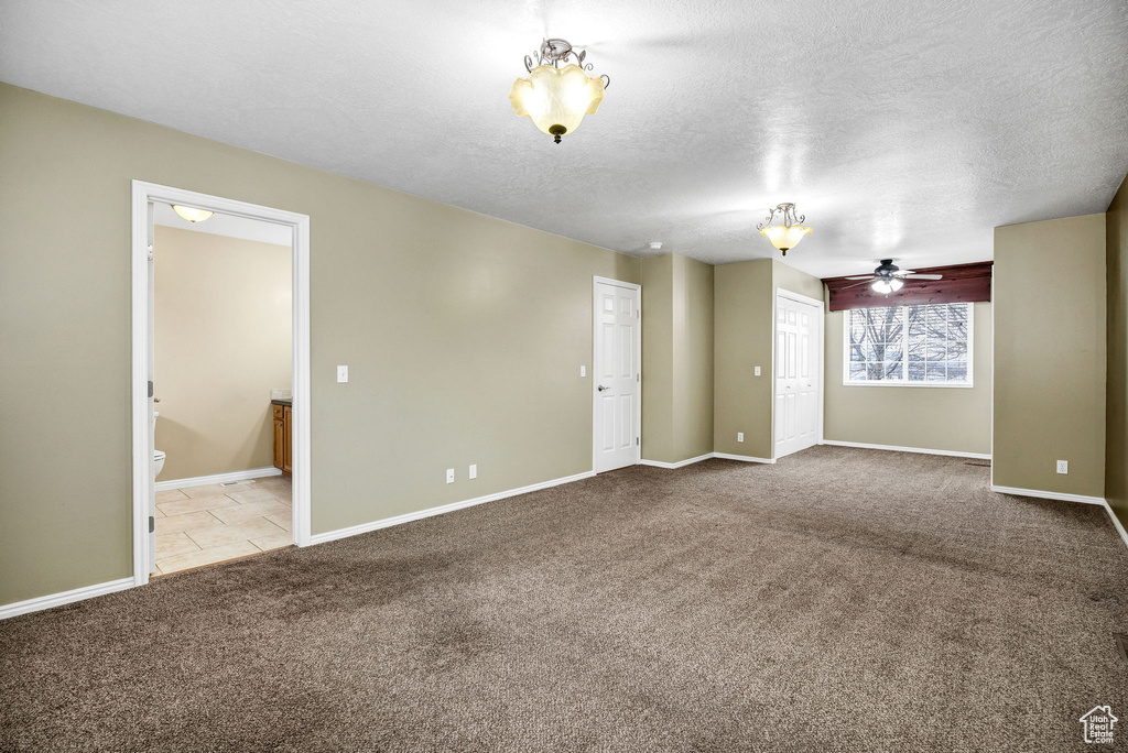 Unfurnished room with ceiling fan, light carpet, and a textured ceiling