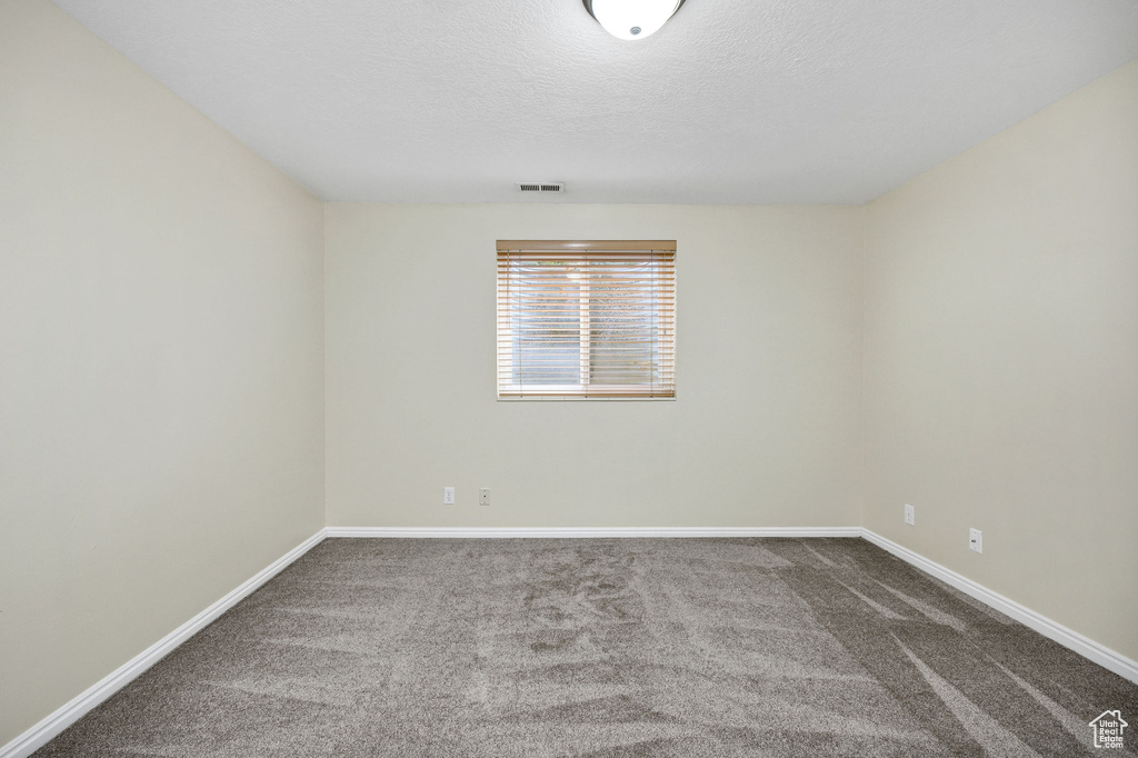 Carpeted empty room with a textured ceiling