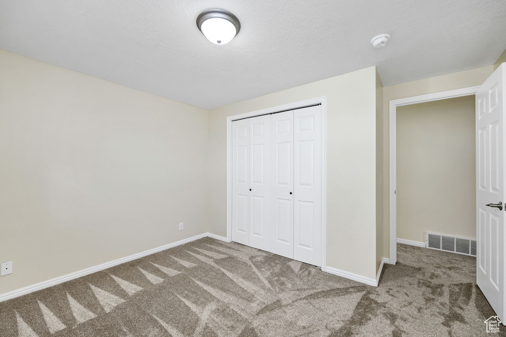 Unfurnished bedroom with a closet, carpet, and a textured ceiling