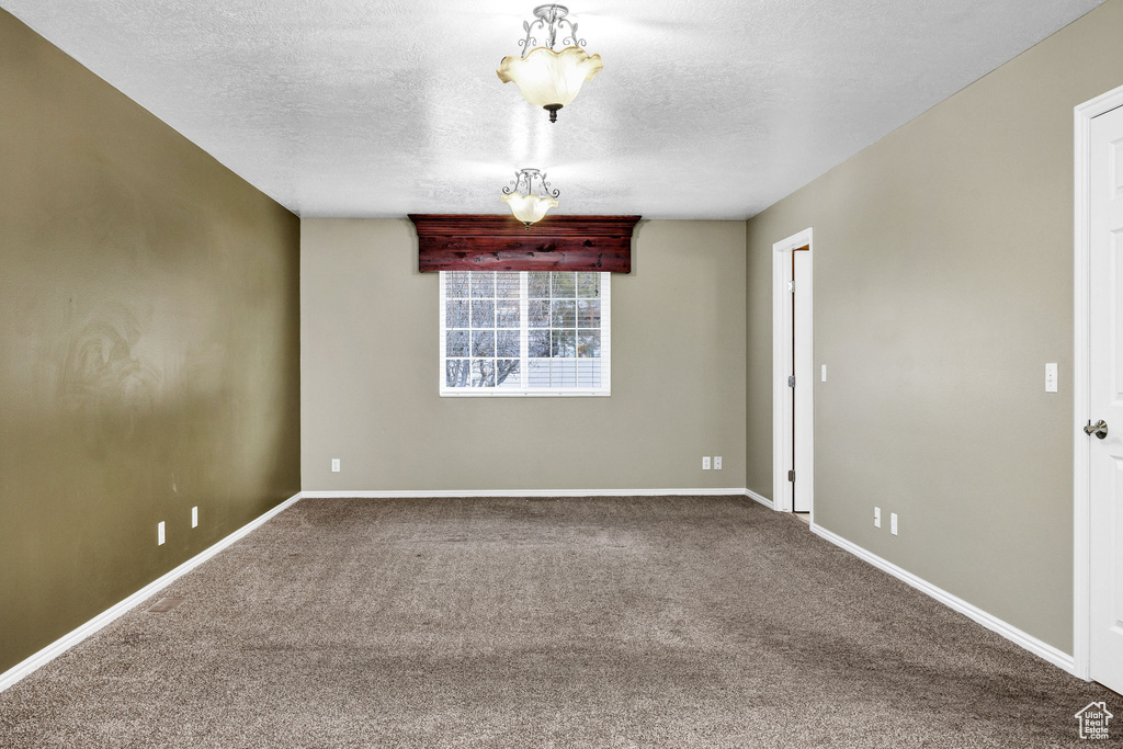 Empty room with carpet and a textured ceiling