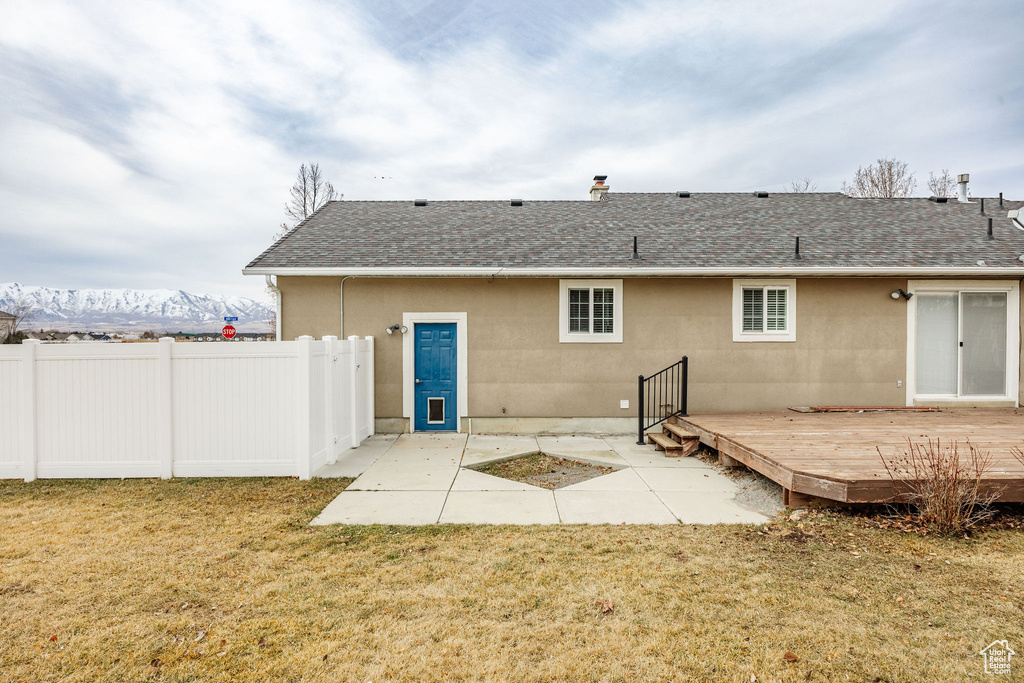 Rear view of house featuring a yard, a patio area, and a deck with mountain view