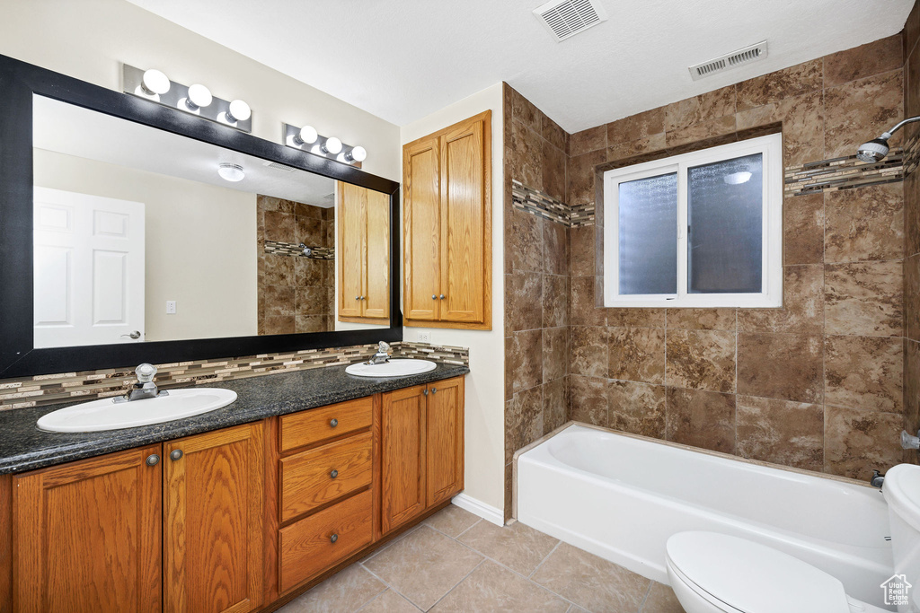 Full bathroom featuring tile patterned flooring, vanity, tiled shower / bath combo, and toilet