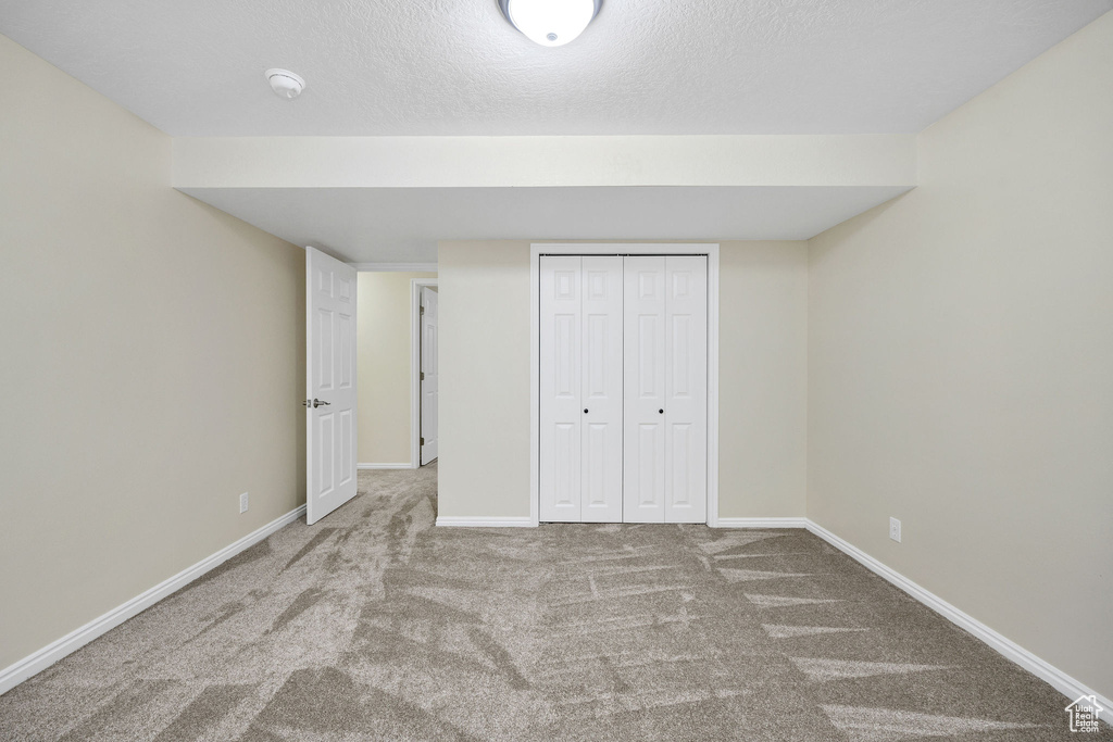 Unfurnished bedroom with carpet floors, a closet, and a textured ceiling