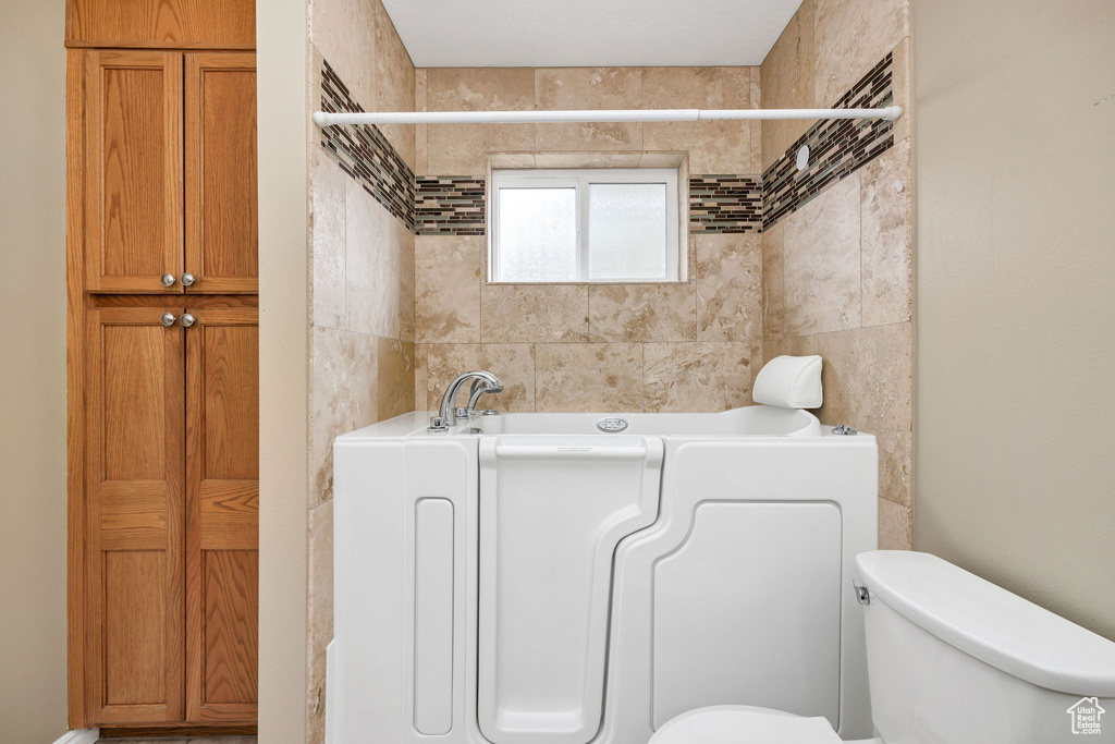 Bathroom featuring a washtub and toilet