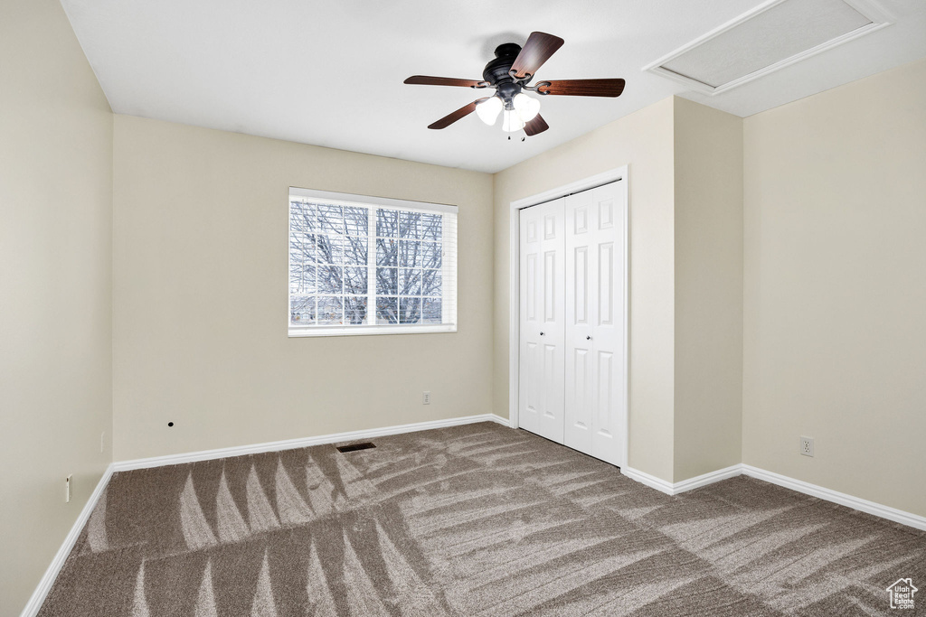 Unfurnished bedroom featuring carpet flooring, ceiling fan, and a closet