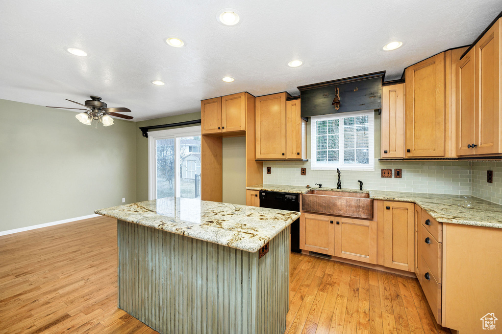 Kitchen with sink, a center island, dishwasher, light stone countertops, and light hardwood / wood-style floors