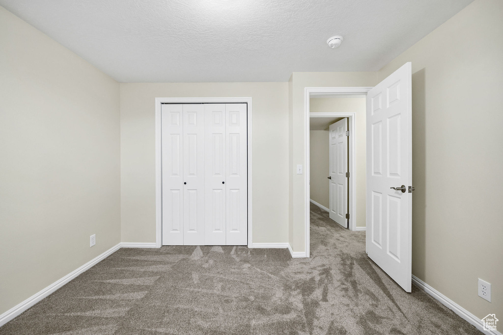 Unfurnished bedroom with a closet, a textured ceiling, and carpet flooring