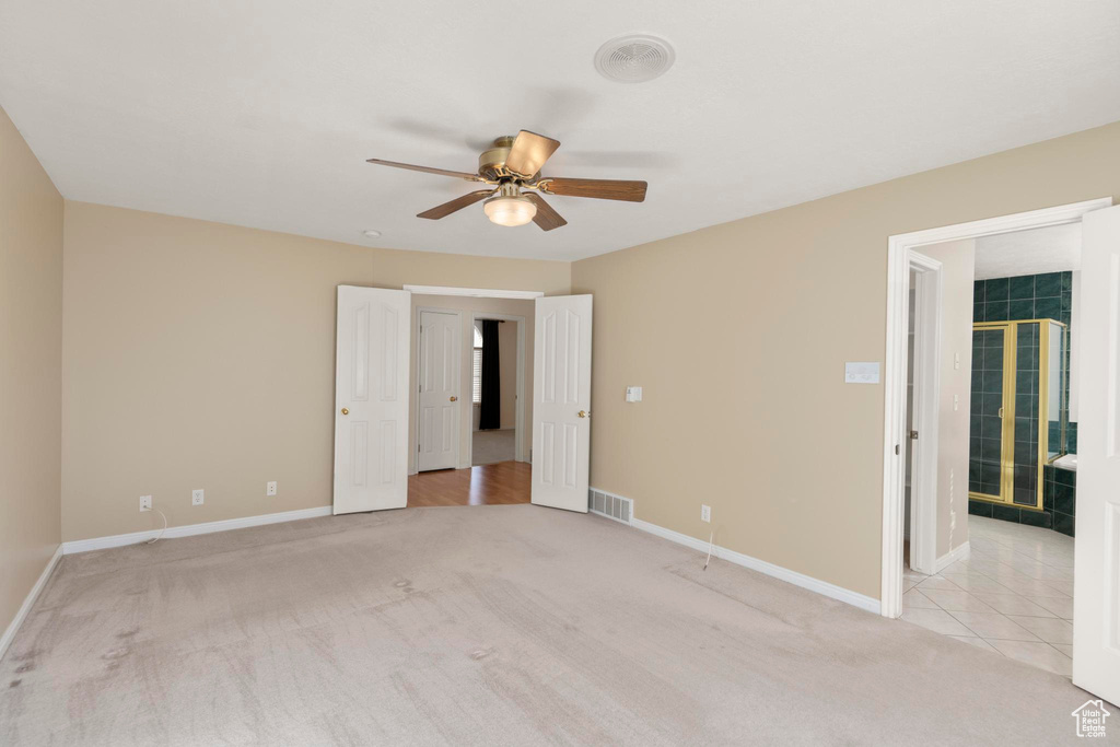 Unfurnished bedroom featuring ceiling fan, visible vents, baseboards, and light carpet