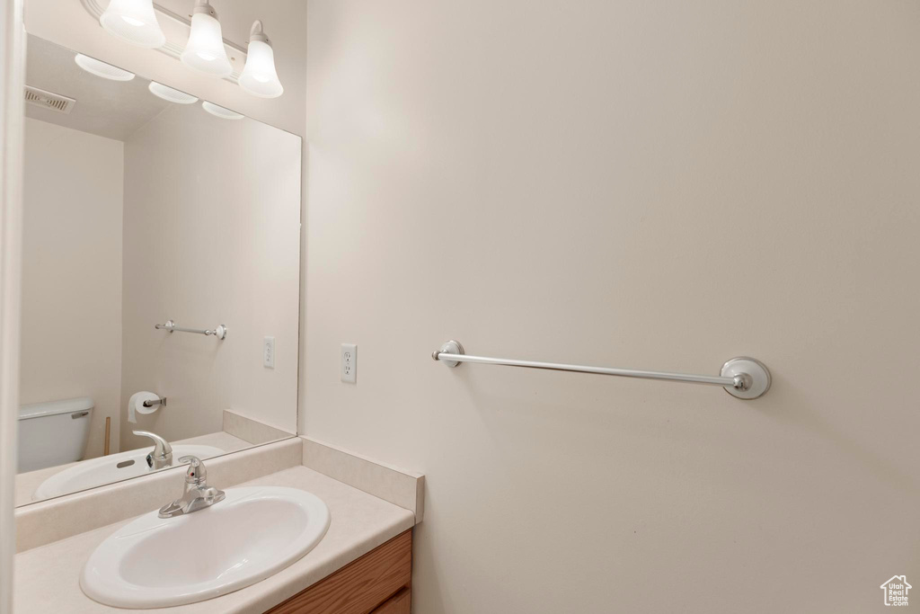 Half bath with toilet, vanity, and visible vents