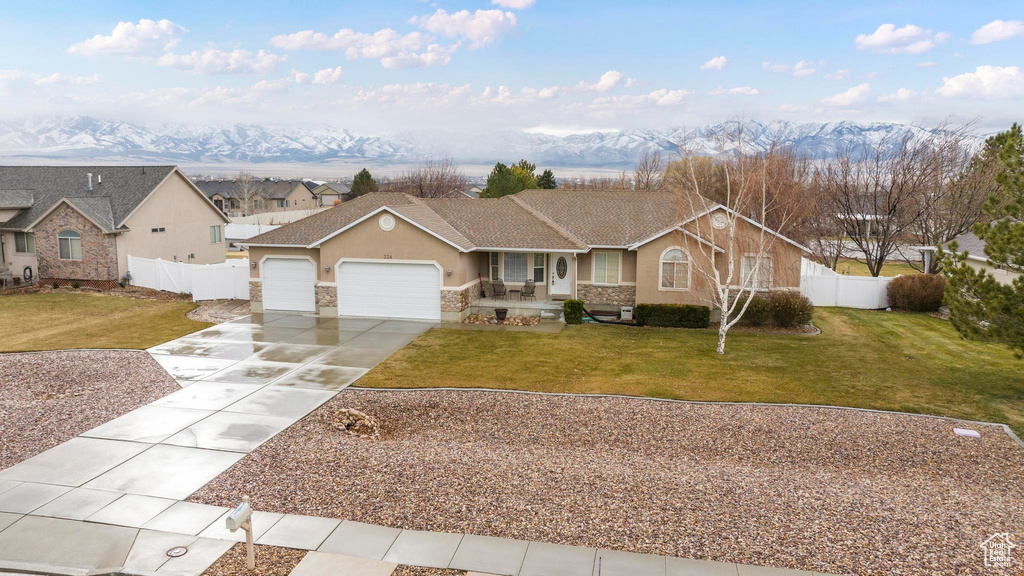 Single story home with concrete driveway, a front lawn, an attached garage, fence, and stucco siding