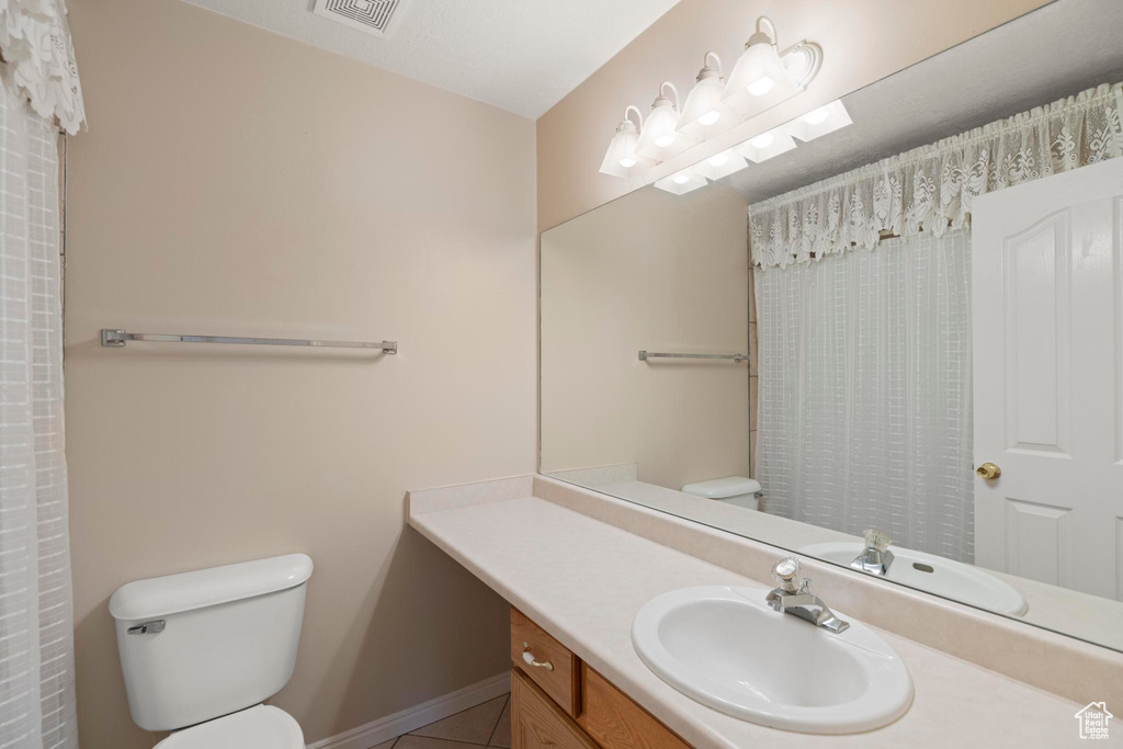 Bathroom featuring vanity, baseboards, toilet, tile patterned flooring, and visible vents