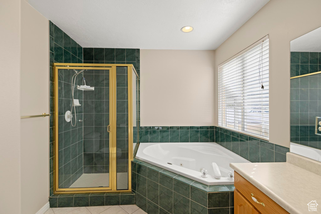 Full bath featuring a shower stall, vanity, tile patterned flooring, and a tub with jets