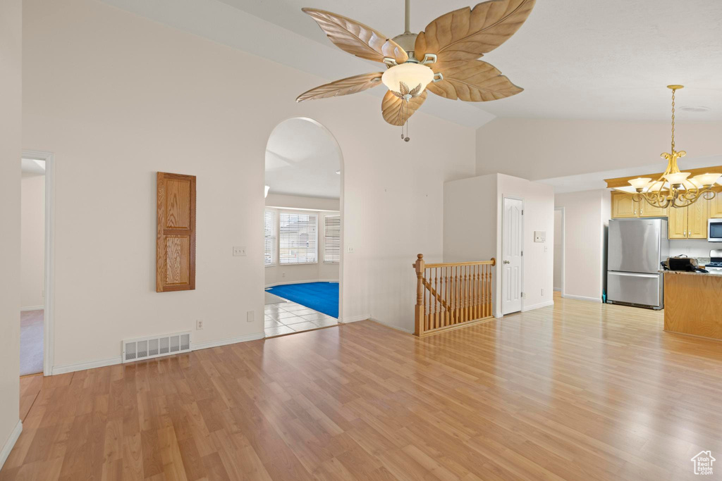 Unfurnished living room featuring baseboards, arched walkways, visible vents, and light wood-style flooring