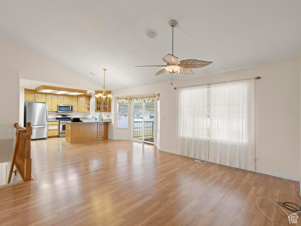 Unfurnished living room with light wood finished floors, high vaulted ceiling, and ceiling fan with notable chandelier