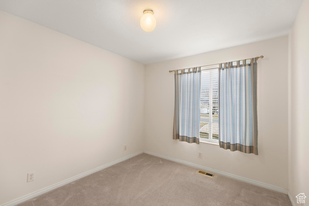 Spare room featuring visible vents, carpet flooring, and baseboards