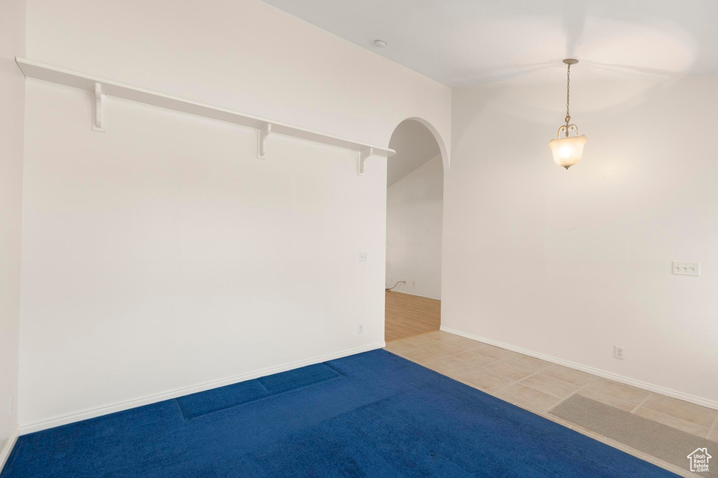 Empty room featuring arched walkways and light tile patterned flooring