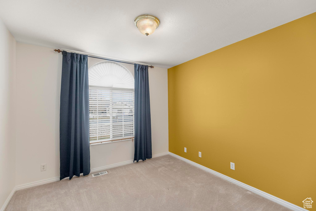 Unfurnished room featuring carpet floors, visible vents, and baseboards