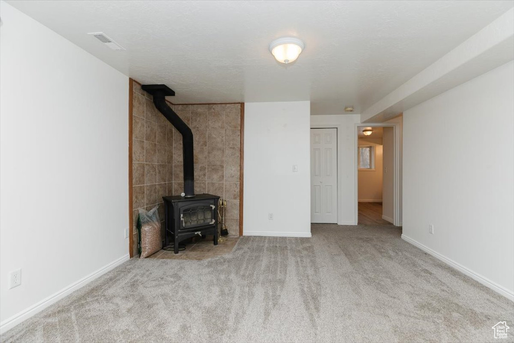 Unfurnished living room featuring a wood stove and light carpet