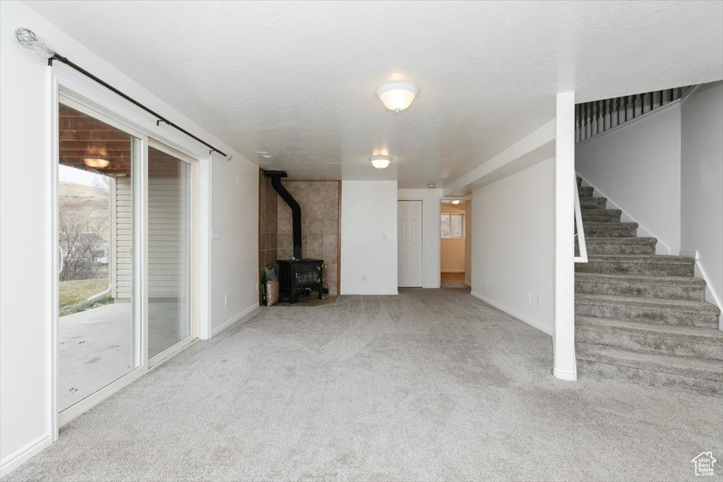 Unfurnished living room with light carpet and a wood stove