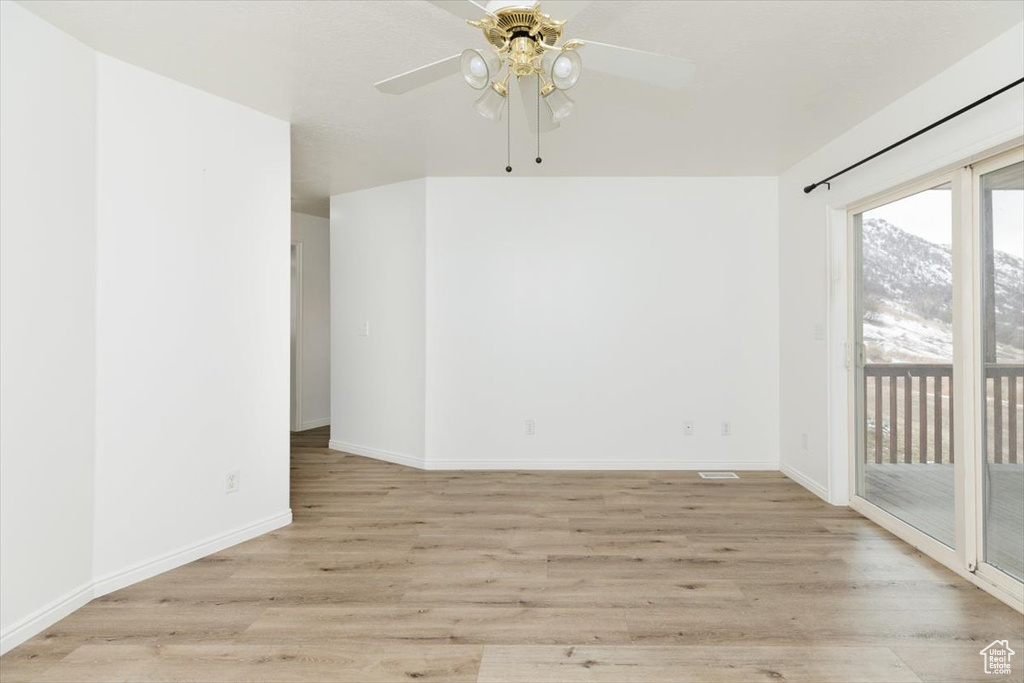 Empty room with ceiling fan and light hardwood / wood-style floors