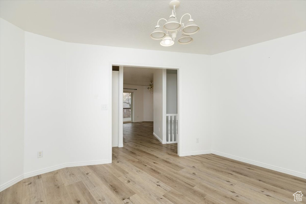 Empty room with an inviting chandelier and light hardwood / wood-style floors