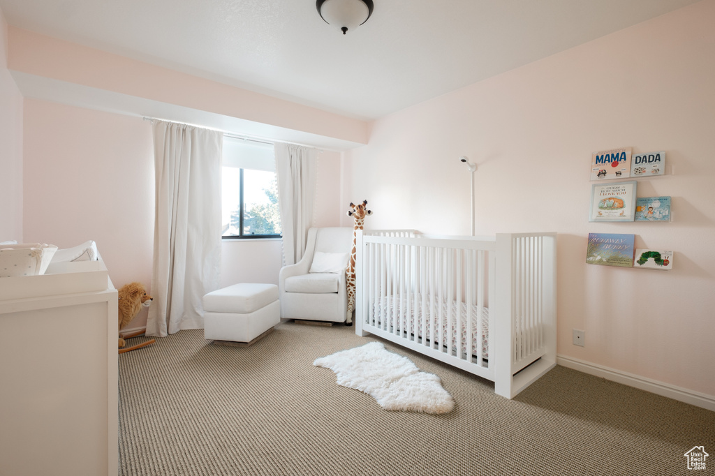 Bedroom with a crib and carpet flooring