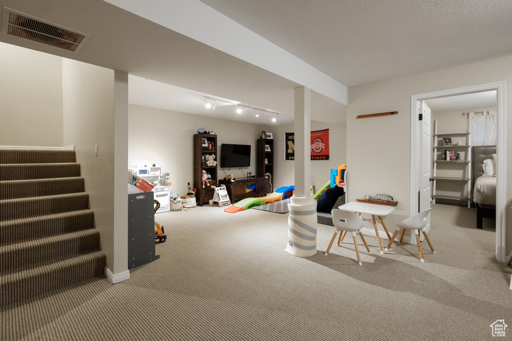 Game room with rail lighting, carpet, and a textured ceiling