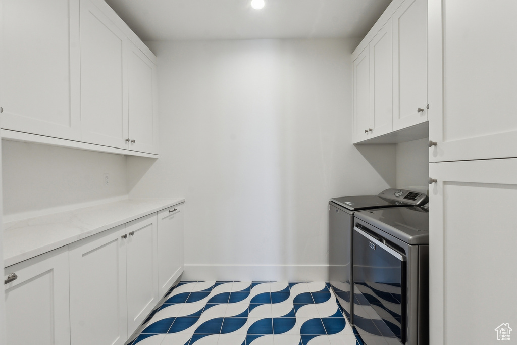 Washroom with cabinets and washing machine and clothes dryer