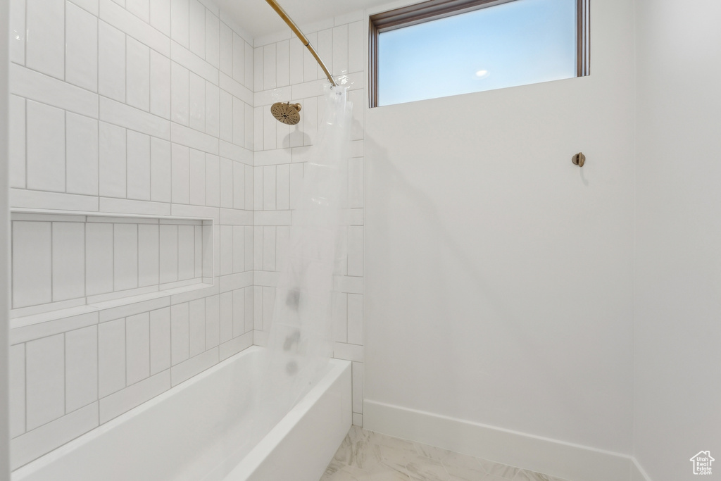 Full bathroom featuring marble look tile flooring, bathtub / shower combination, and baseboards