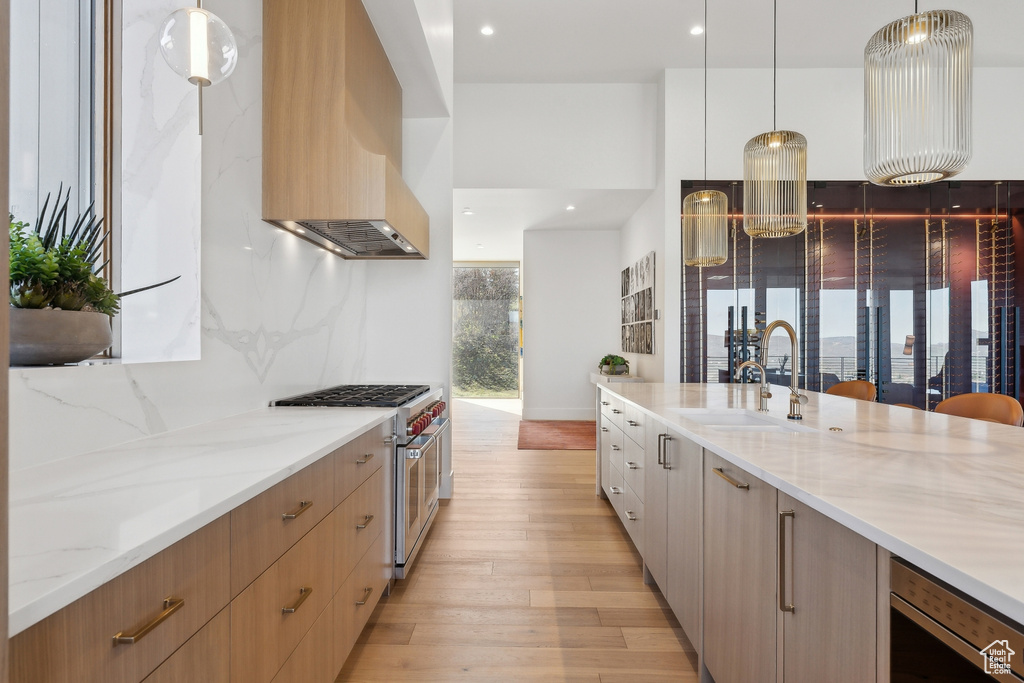 Kitchen featuring high end stove, custom exhaust hood, a sink, modern cabinets, and recessed lighting