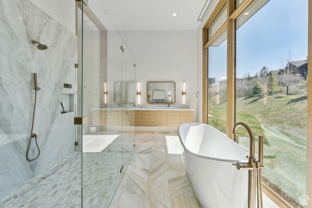 Bathroom with a marble finish shower, a freestanding bath, double vanity, and recessed lighting