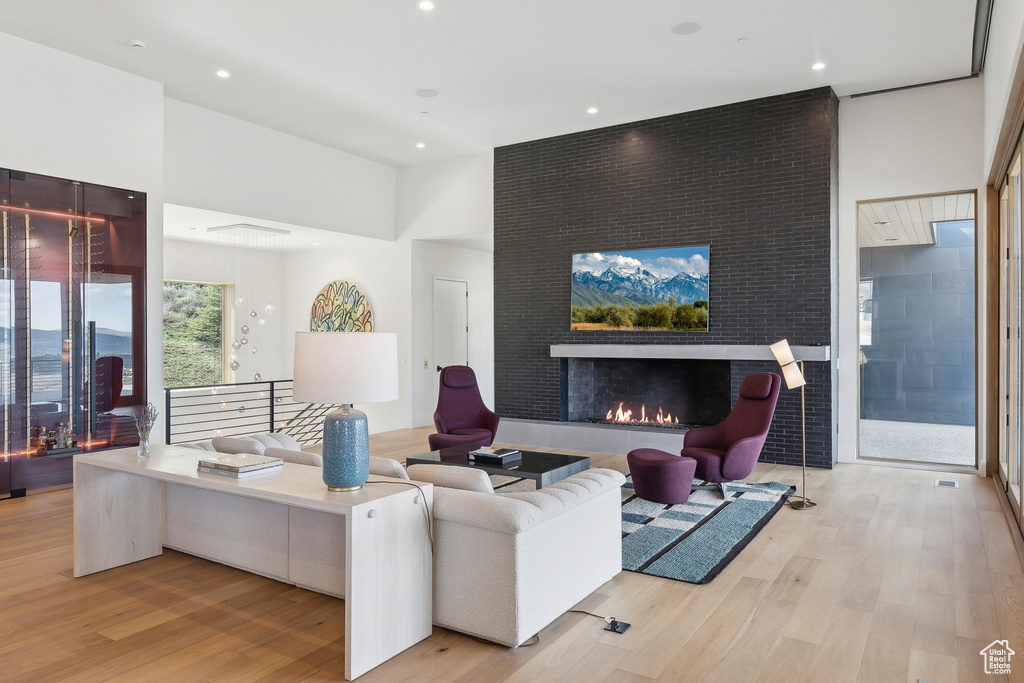 Living area with wood finished floors, a large fireplace, and recessed lighting
