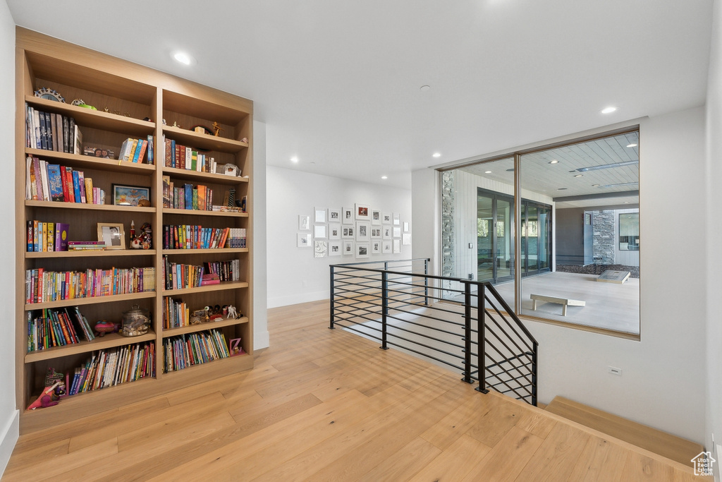 Hall with an upstairs landing, wood finished floors, baseboards, and recessed lighting