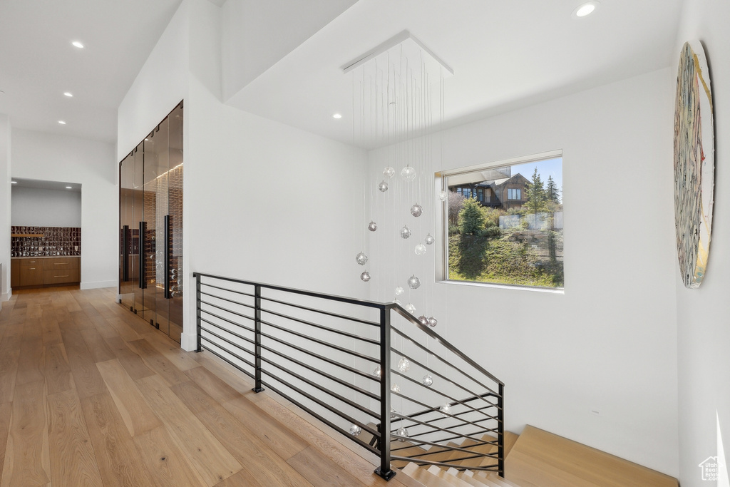 Corridor with an upstairs landing, light wood-style floors, and recessed lighting