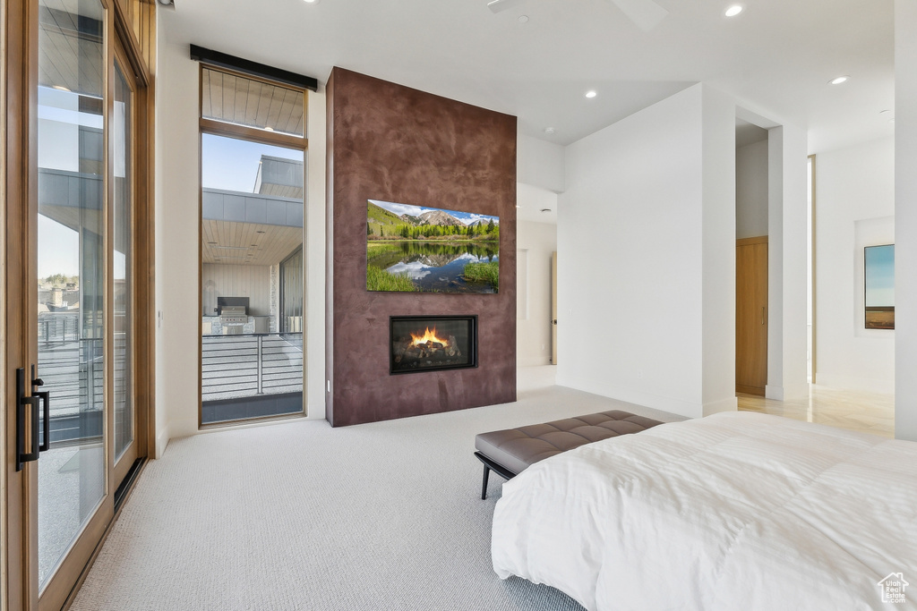 Carpeted bedroom featuring access to outside, a large fireplace, and recessed lighting