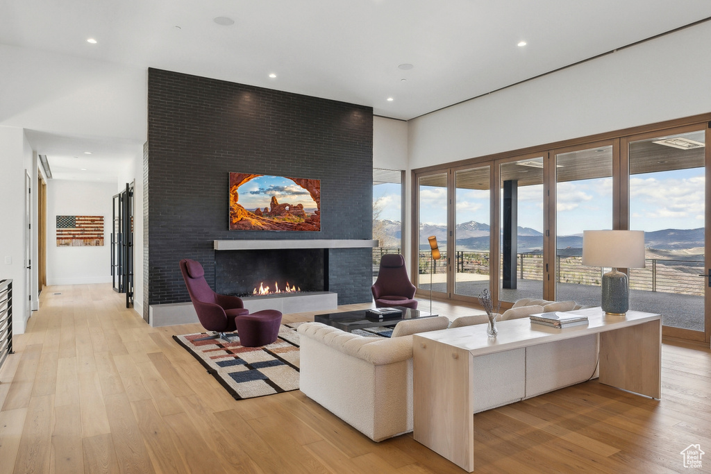 Living room featuring a mountain view, light wood finished floors, a large fireplace, and recessed lighting