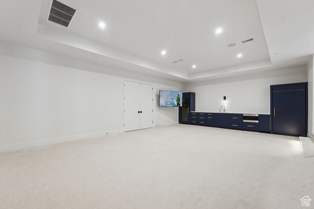 Carpeted empty room featuring a tray ceiling