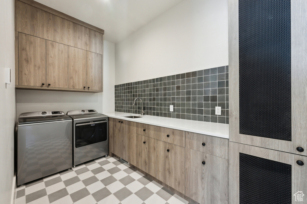 Clothes washing area with sink, washer and clothes dryer, and cabinets