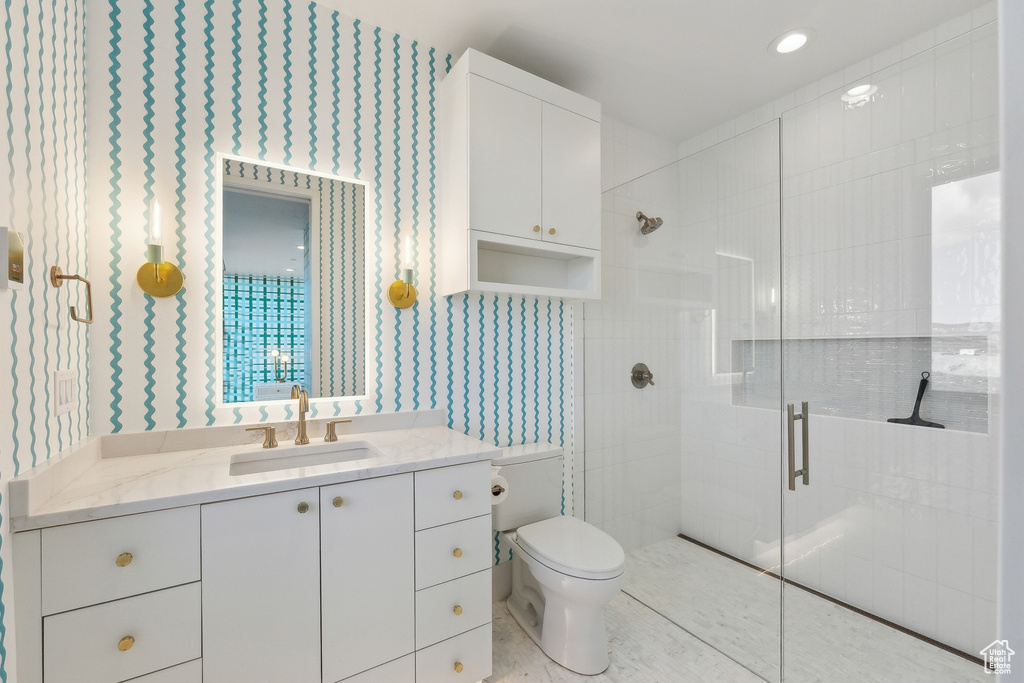 Full bathroom with a stall shower, toilet, vanity, and wallpapered walls