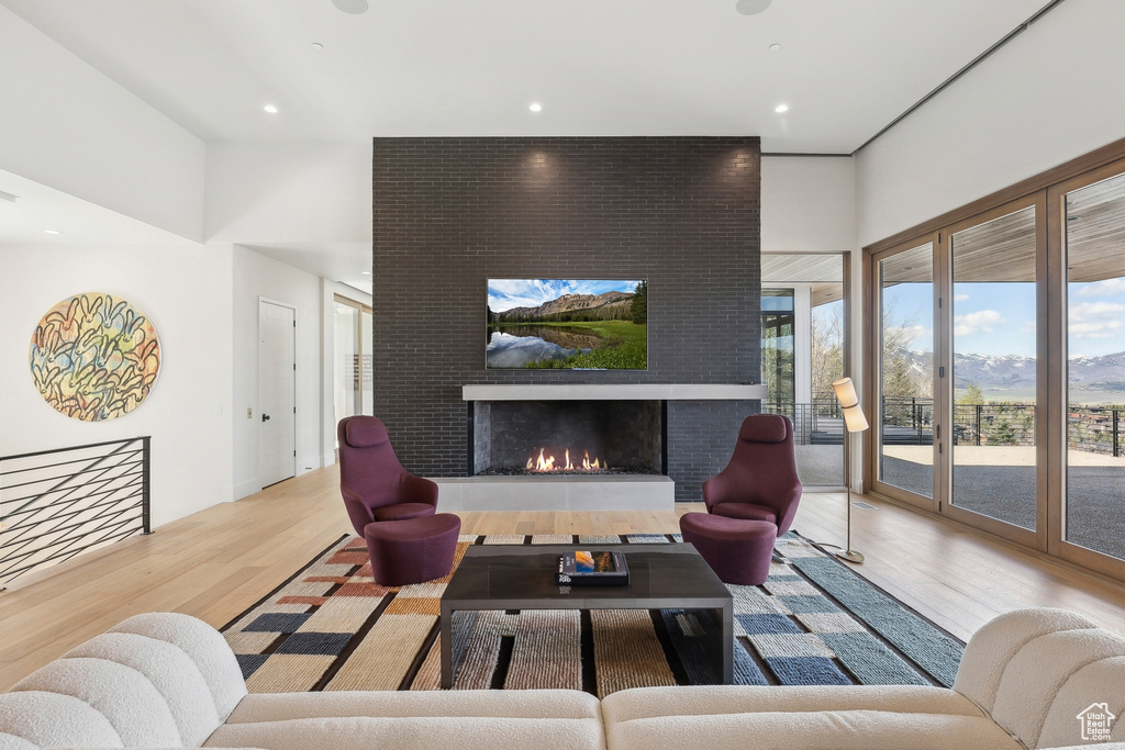 Living room with wood finished floors, a large fireplace, and recessed lighting