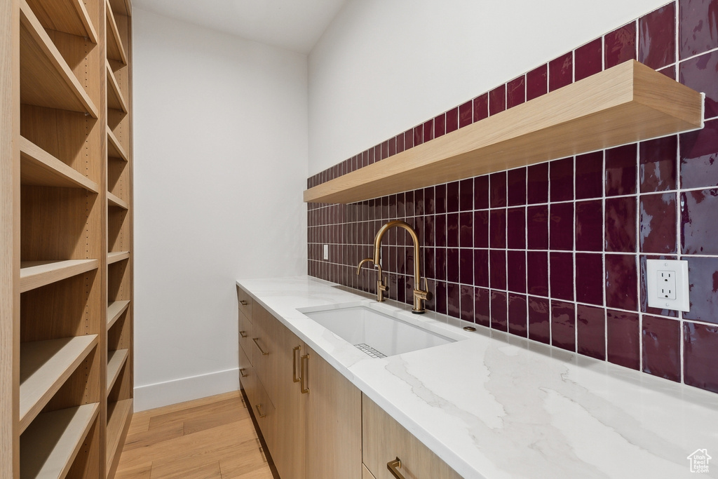 Interior space featuring a sink, light wood-style floors, backsplash, and baseboards
