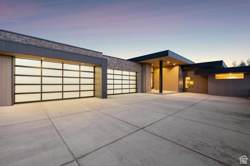 Contemporary home with concrete driveway, an attached garage, and stone siding
