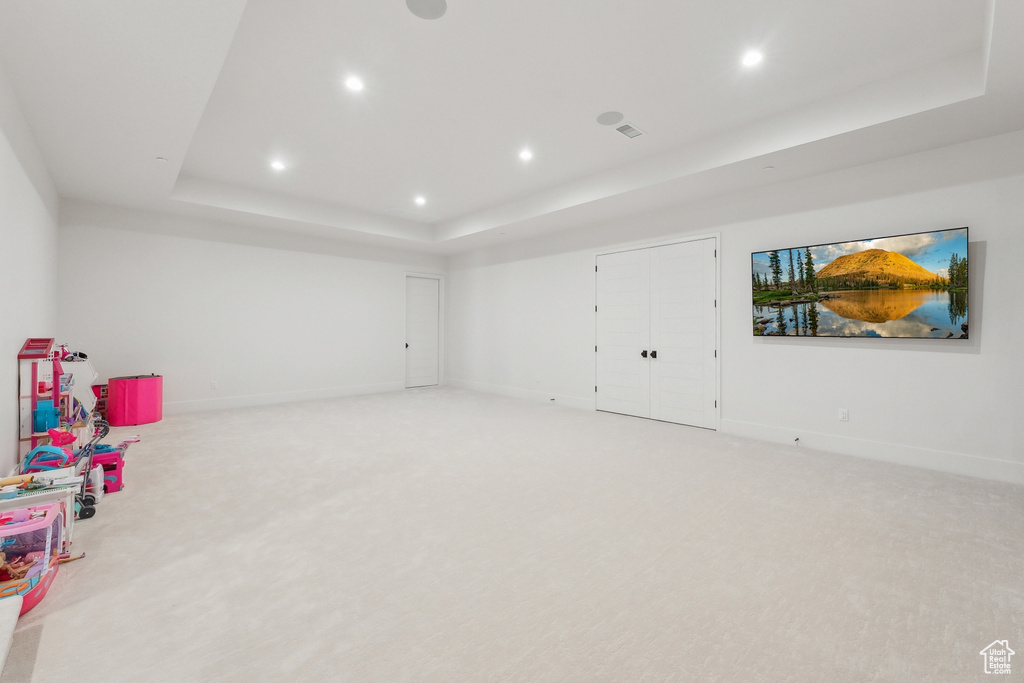 Recreation room with a tray ceiling, light colored carpet, recessed lighting, and baseboards