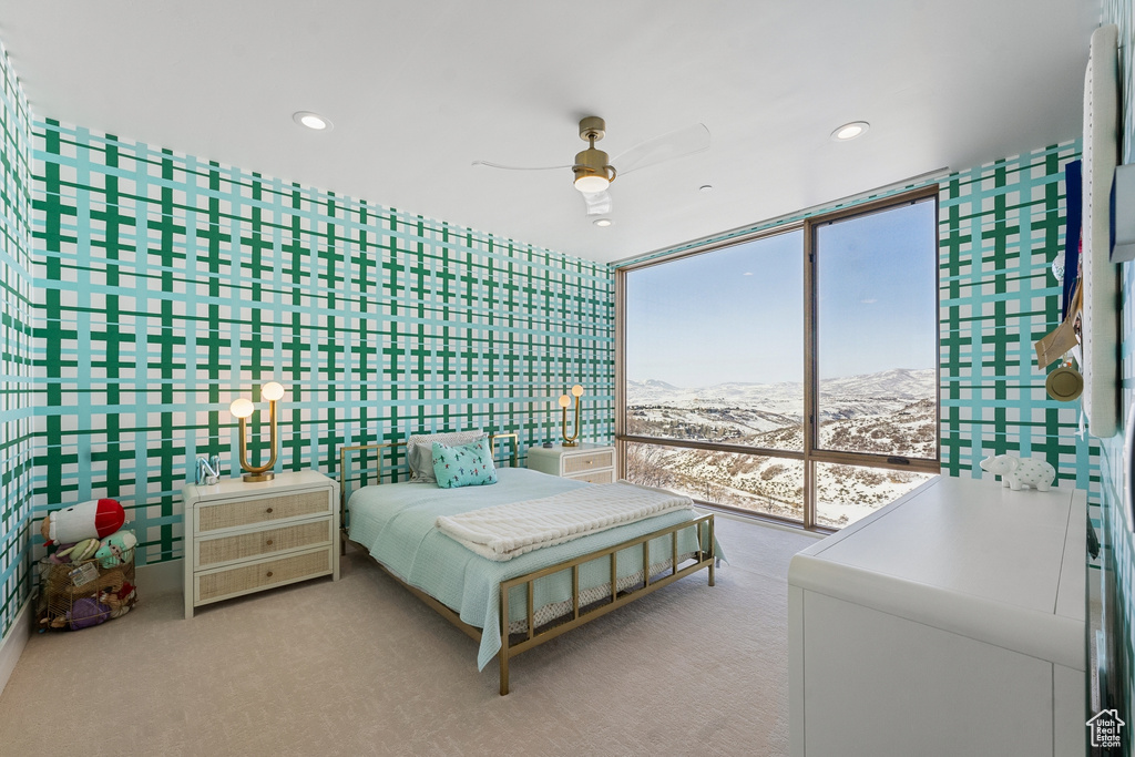 Carpeted bedroom featuring a mountain view, floor to ceiling windows, and ceiling fan