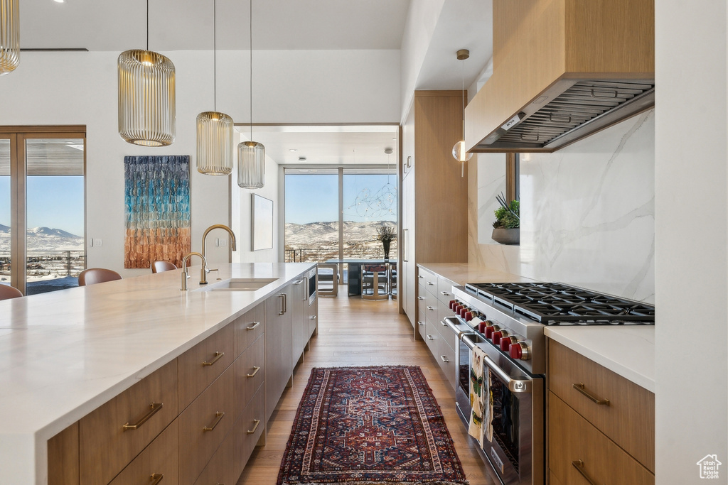 Kitchen with custom exhaust hood, decorative light fixtures, a mountain view, and high end stove