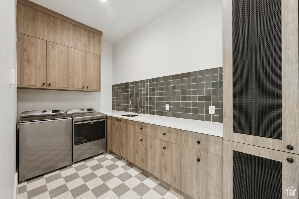 Washroom featuring cabinet space, washer and dryer, and light floors