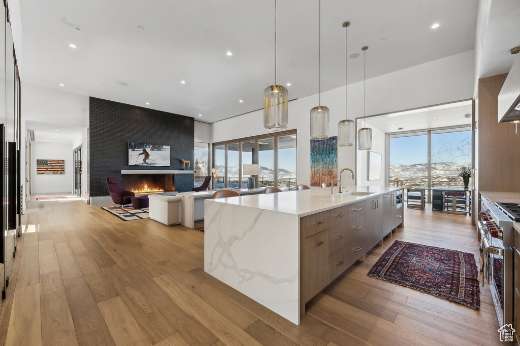 Kitchen featuring a spacious island, light wood-type flooring, light stone counters, and pendant lighting