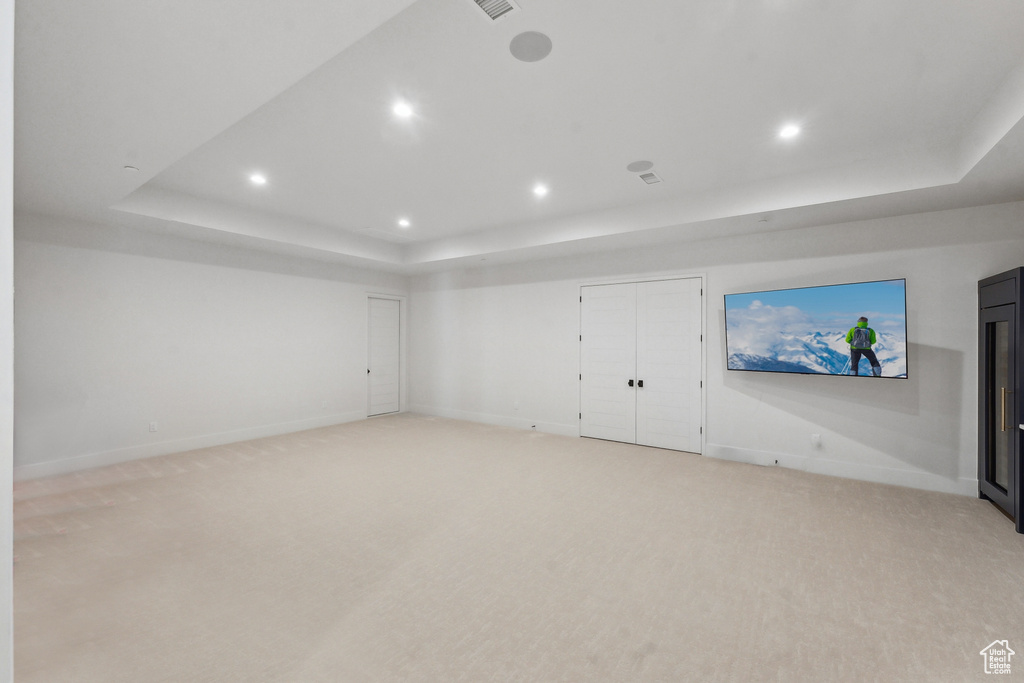 Interior space featuring a raised ceiling and light carpet