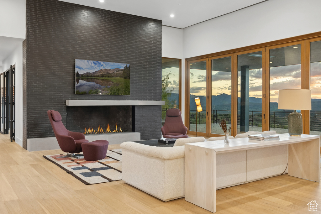 Living room with wood finished floors, a large fireplace, a high ceiling, and recessed lighting